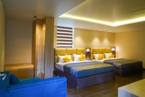 a bedroom with two beds with yellow pillows at Trident in Ooty