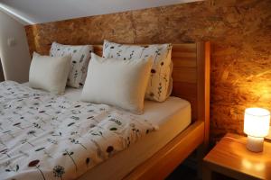 a bed with white pillows and a lamp on a table at Green Valley Apartments in Zavrč
