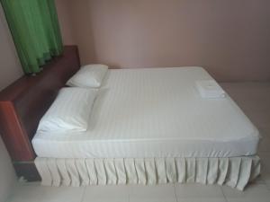 een bed met witte lakens en kussens in een kamer bij เรือนแสนรัก รีสอร์ท in Ban Nong Ket Yai