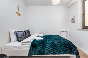 a white bedroom with a green blanket on a bed at Miedziana 14 by Homeprime in Warsaw