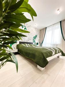 a bedroom with a green bed and a large plant at Jungle Apartments in Vinnytsya