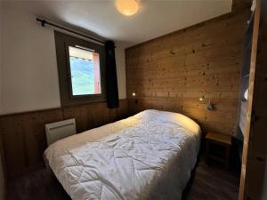 een slaapkamer met een wit bed en een raam bij Résidence Courmayeur - 2 Pièces pour 4 Personnes 934 in Les Menuires