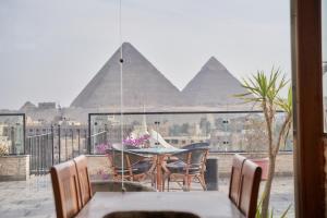 a woman sitting at a table on a balcony with the pyramids at Top pyramids hotel in Cairo