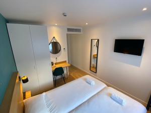 Schlafzimmer mit einem weißen Bett und einem Schreibtisch in der Unterkunft Oskar Hotel in Annemasse
