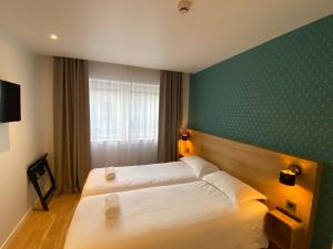 a hotel room with two beds and a green wall at Oskar Hotel in Annemasse