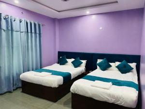 2 Betten in einem Zimmer mit lila und lila Wänden in der Unterkunft Hotel Mangalam in Siddharthanagar