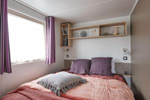 sypialnia z łóżkiem z fioletowymi poduszkami i oknem w obiekcie Camping het Wieskamp w mieście Henxel