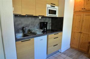 a kitchen with a sink and a microwave at Résidence Beaufortain - Studio pour 4 Personnes 024 in Les Menuires