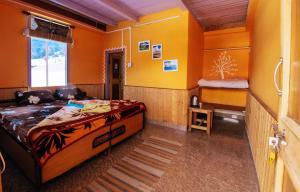 um quarto com paredes cor de laranja e uma cama num quarto em Suhaana Ghar em Sainj