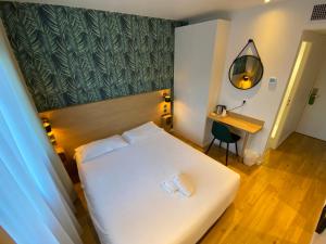 een hotelkamer met een wit bed en een bureau bij Oskar Hotel in Annemasse