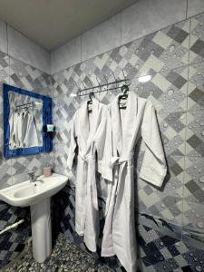 een badkamer met een wastafel en witte badjassen bij OS Rill in Samarkand +9 foto's
