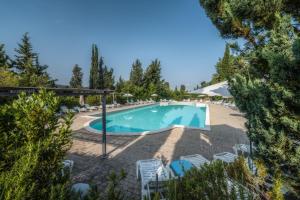 een zwembad in een resort met stoelen en een parasol bij Il Cigliere Wellness Spa Resort in Riparbella