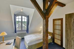 1 dormitorio con cama, escritorio y ventana en Sorell Hotel Rüden, en Schaffhausen