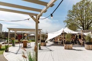 un patio al aire libre con tiendas y mesas y personas sentadas en mesas en Hotel Den Berg, en Londerzeel