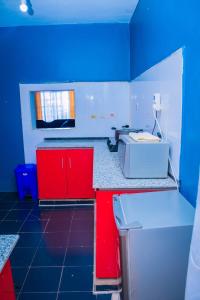 uma cozinha azul e branca com armários vermelhos e um lavatório em Kisumu Cozy Apartments em Kisumu