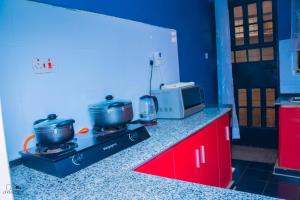 uma cozinha com um fogão com 2 panelas e um micro-ondas em Kisumu Cozy Apartments em Kisumu