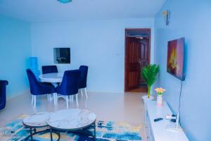 uma sala de estar azul com uma mesa e cadeiras em Kisumu Cozy Apartments em Kisumu