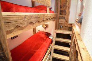 a room with two bunk beds with red sheets at Résidence Necou - Studio pour 3 Personnes 954 in Les Menuires