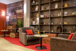 SOWELL HOTELS Le Parc & Spa في بريانسو: غرفة معيشة مع كرسيين وطاولة ورفوف