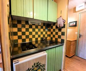 een keuken met groene kasten en een wastafel bij Résidence Alpages - Studio pour 3 Personnes 904 in Les Menuires