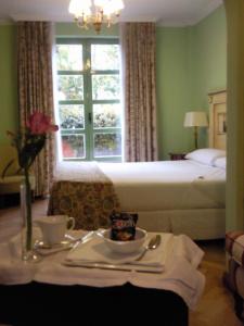 a hotel room with a bed and a table with a tray of food at La Quinta de los Cedros in Madrid