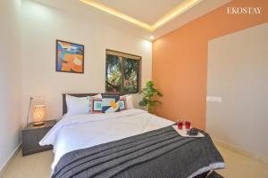 a bedroom with a large bed with orange walls at EKOSTAY - Bloomfield Villa in Alibaug