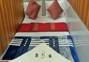 uma cama com um cobertor e almofadas brancos e azuis vermelhos em HOTEL AMAAN PALACE em Mumbai