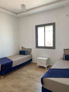1 dormitorio con 2 camas y ventana en Maison de Noé Djerba Midoun en Midoun