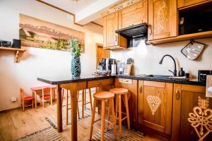 a kitchen with wooden cabinets and a counter with stools at Domek u Zosi in Zakopane