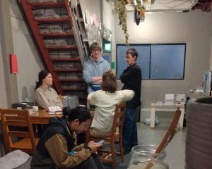 un groupe de personnes debout dans une pièce dans l'établissement TONARINO Hostel for Backpackers, à Kobe