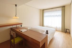 a bedroom with a bed and a desk and a window at Mooke&Co Moganshan in Deqing