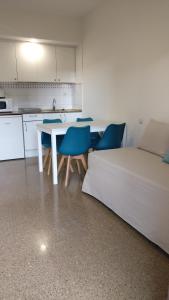 cocina con mesa blanca y sillas azules en Aparthotel Las Mariposas en Lloret de Mar