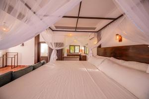 BeliattaにあるVillage Paradiseのベッドルーム(大きな白いベッド、カーテン付)