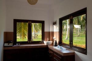 a bathroom with two windows and a white sink at Village Paradise in Beliatta +39 photos