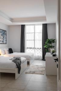 a white bedroom with two beds and a window at 3 Bedroom Apartment in Riyadh