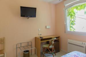 a bedroom with a desk and a tv on the wall at Hôtel du Canal in Castelnaudary