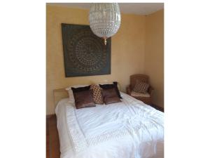 um quarto com uma cama branca e um lustre em Maison Les Bardots em Savignac-de-Duras