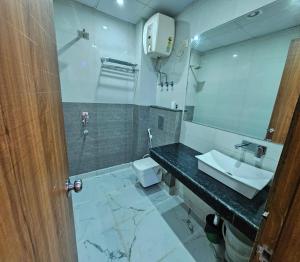 a bathroom with a sink and a toilet and a mirror at Hotel Linda Suites Near International Airport By LA CASA in New Delhi