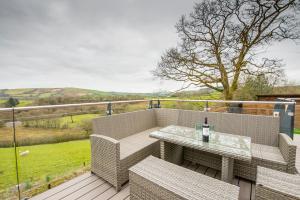 a patio with a table and chairs on a deck at Tranquil house with hot tub BBQ wheelchair access in Llandeilo