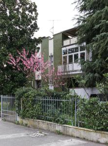 a house with pink flowers in front of a fence at Flytosuite Aeroporto Penthouse Attic Room in Calderara di Reno