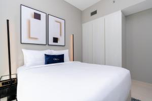 Un dormitorio blanco con una gran cama blanca y cuadros enmarcados. en CitiHome - Newly Furnished Apartment in Business Bay, en Dubái