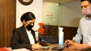 a woman wearing a mask sitting at a desk at Hotel Jageer Palace Bawana in Bawāna