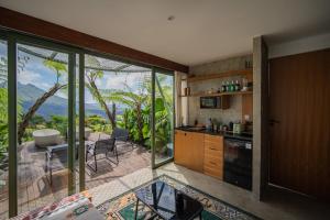 a kitchen with sliding glass doors and a view of the ocean at Black Wood Cabin in Kintamani