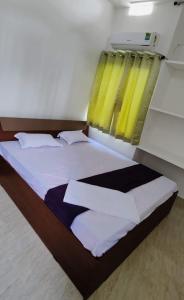Schlafzimmer mit einem großen Bett und gelben Vorhängen in der Unterkunft Glamour Palace in Bodh Gaya