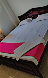 1 dormitorio con 1 cama grande con sábanas rosas y grises en Glamour Palace, en Bodh Gaya