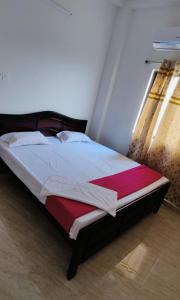 una camera con un letto con una coperta rossa e bianca di Glamour Palace a Bodh Gaya