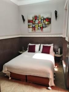 een slaapkamer met een groot wit bed met rode kussens bij Dar Nassima in Marrakesh