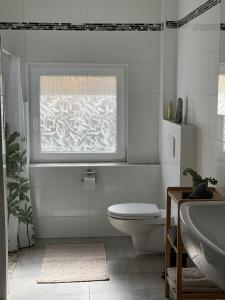 a white bathroom with a toilet and a window at Bohlinger Seeapartments in Bohlingen