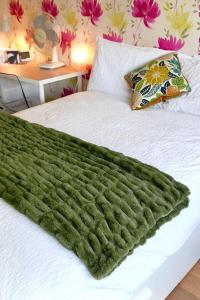 a green blanket laying on top of a bed at Anna's House in Ickleford