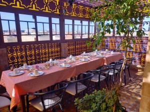 a long tables and chairs in a room with windows at Riad Mehdi Meknès in Meknès